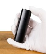 PAX Plus Vaporizer in einer Hand mit weißen Handschuhen gehalten.