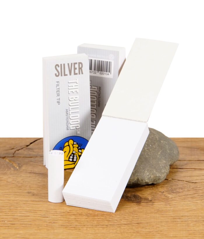 Geöffnete Packung The Bulldog Silver Filter Tips mit einzelnen Filtertips auf einem Stein präsentiert.