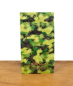 Der Black Leaf Zipperbeutel mit Hanfblatt-Camouflage-Design steht aufrecht auf einer Holzoberfläche. Das Black Leaf-Logo und der Schriftzug „In Weed We Trust“ sind sichtbar.