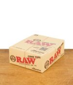Geschlossene Verkaufsbox der RAW Cone Tips Maestro mit 24 Heftchen, platziert auf einer Holzoberfläche.