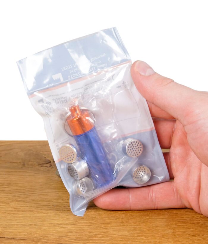 Hand hält den originalverpackten Storz & Bickel Kapselbehälter mit mehreren Dosierkapseln in einer durchsichtigen Tüte.