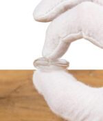 Weiß behandschuhte Hand hält einen kleinen, klaren Glasaufsatz mit schmaler Öffnung.