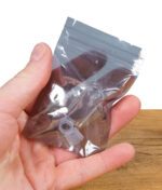 Hand hält eine kleine, transparente Verpackung mit einem Glasaufsatz und Silikonringen.