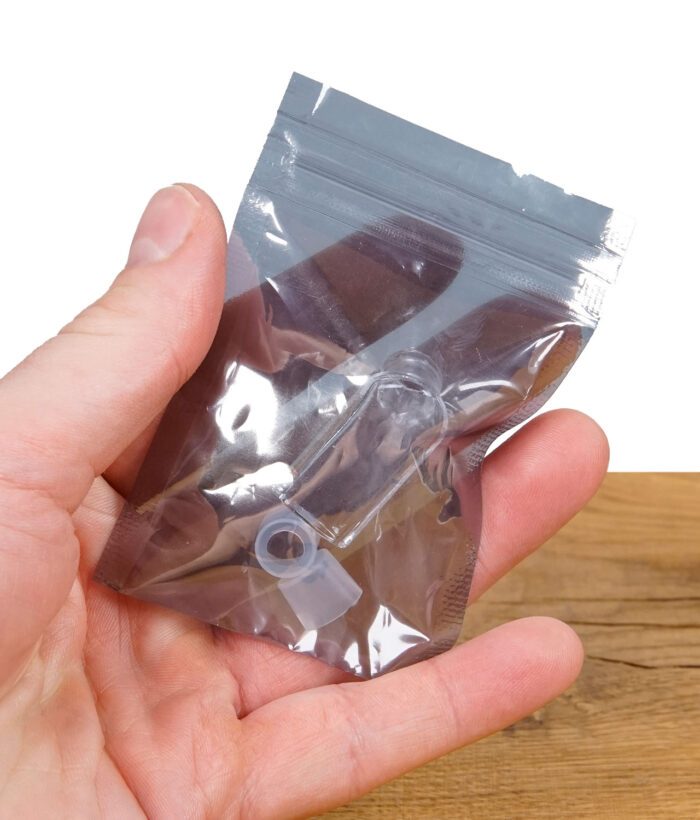 Hand hält eine kleine, transparente Verpackung mit einem Glasaufsatz und Silikonringen.