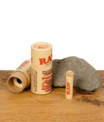 RAW Rose Tip – vorgerollter Filter mit kunstvoller Rosenspitze in umweltfreundlicher Kartonverpackung auf Holztisch mit Stein.
