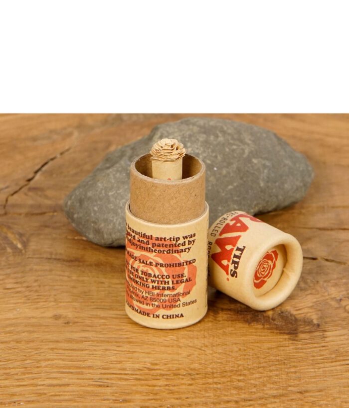 RAW Rose Tip im offenen Kartonbehälter mit kunstvoll gefalteter Rosenspitze, platziert auf einem Holztisch neben einem Stein.