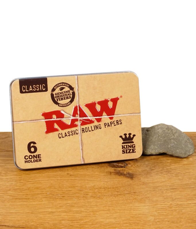 RAW Classic Cone Holder – Metalldose für King Size Cones mit klassischem RAW-Design, platziert auf einem Holztisch mit Stein.