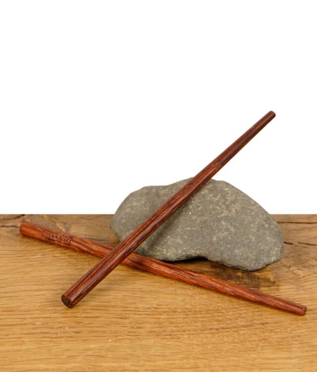 Zwei RAW Wooden Pokers – Holztamper für Cones, gekreuzt auf einem Stein liegend, präsentiert auf Holztisch.