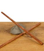 Zwei RAW Wooden Pokers – lange Holztamper für Cones, gekreuzt auf einem Stein liegend, präsentiert auf Holztisch.