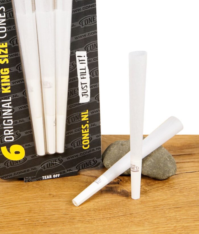 Nahaufnahme der The Original King Size Cones Packung mit sechs vorgedrehten Cones, daneben lose Cones auf Holztisch mit Stein.