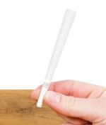 The Original King Size Cone – weißer vorgedrehter Cone mit Filter, gehalten zwischen Daumen und Finger vor Holztisch-Hintergrund.