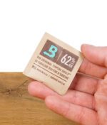 Boveda 62% Feuchtigkeitspack – in der Hand gehalten, zeigt das Logo und die Feuchtigkeitskontrolle für Kräuterlagerung.