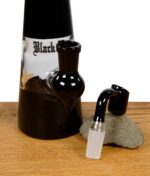 Black Leaf Dab-Rig in Schwarz mit passendem Banger, beides auf einem Stein platziert.