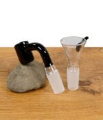 Schwarzer Banger und passender Glaskopf mit NS-Schliff, auf Stein und Holz platziert.