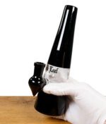 Black Leaf Dab-Rig wird von einer Hand in weißen Handschuhen gehalten.