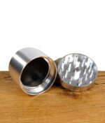 Zerlegter True Fruits Grinder aus Aluminium auf Holztisch.