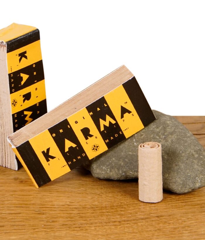 Karma Filtertips Booklet mit offenem Filtertip und einzelnen, perforierten Blatt auf Naturstein und Holztisch.