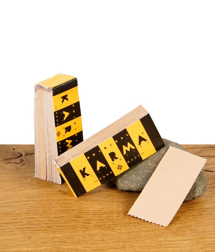 Karma Filtertips Booklet mit handgerolltem Filtertip auf Naturstein und Holztisch.