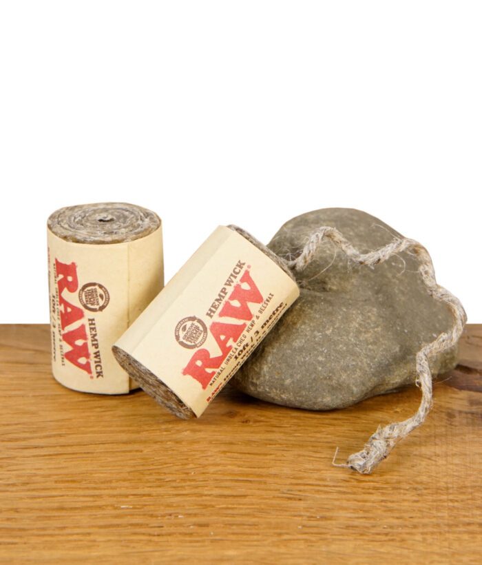 Zwei RAW Hemp Wick Rollen aus Hanf und Bienenwachs auf Stein und Holztisch arrangiert.