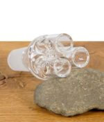 Glasadapter mit drei Öffnungen für Bongköpfe auf Naturstein und Holztisch liegend.