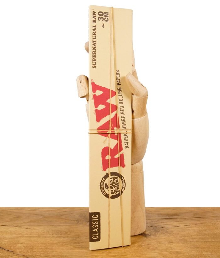 RAW Supernatural Rolling Papers Classic 30 cm Packung in Holzhand auf Holzuntergrund