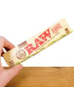 Hand hält eine geschlossene Packung RAW Organic Hemp Cones King Size 32er Pack aus naturbelassenem Hanfpapier