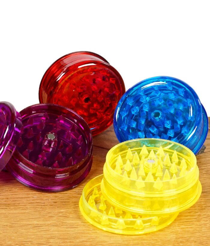 Mehrere Black Leaf Grinder Acryl 60mm in Rot, Gelb, Blau und Lila auf Holztisch gruppiert