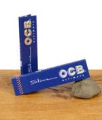 Zwei geschlossene Packungen der OCB Ultimate Slim Papers King Size mit holografischem Logo auf blauem Hintergrund.