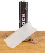 Einzelnes OCB Premium King Size Slim Paper vor stehender Verpackung, ultradünn und leicht transparent.