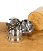 Zerlegter Black Leaf Grinder mit Bambusdeckel und drei Metallteilen auf Holztisch.