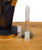 Zubehörteile der Bong: Glaskopf und Diffusor chillen vor der gold-schwarzen Base auf Holztisch.