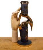 Goldene Design-Bong mit Wabenstruktur im Größenvergleich neben einer Holzhand.