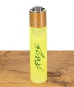 Leuchtend gelbes Clipper Feuerzeug im Purize Design stehend auf Holzoberfläche