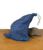 Blauer Stoffbeutel mit Kordelzug auf Holztisch vor hellem Hintergrund