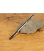 Puffco Dab Tool aus Edelstahl mit Gravur auf einem Stein liegend