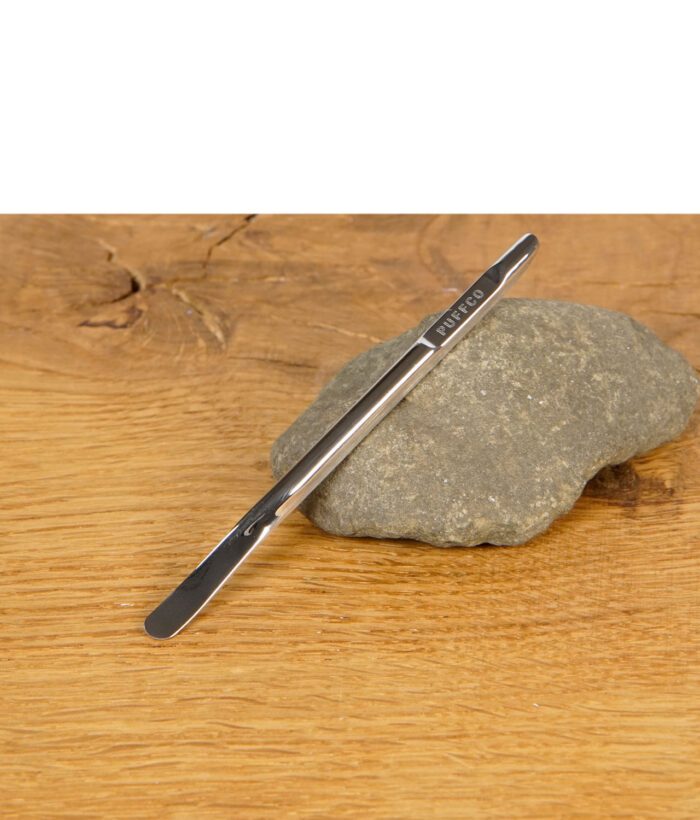 Puffco Dab Tool aus Edelstahl mit Gravur auf einem Stein liegend