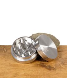 Geöffneter Black Leaf Edelstahlgrinder, 2-teilig mit 39 mm Durchmesser, liegend auf Holztisch – Schleifzähne und Deckel sichtbar