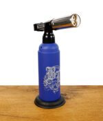 Black Leaf Butangasbrenner in Blau mit Doppelbrennerkopf und Standfuß, stehend auf Holztisch