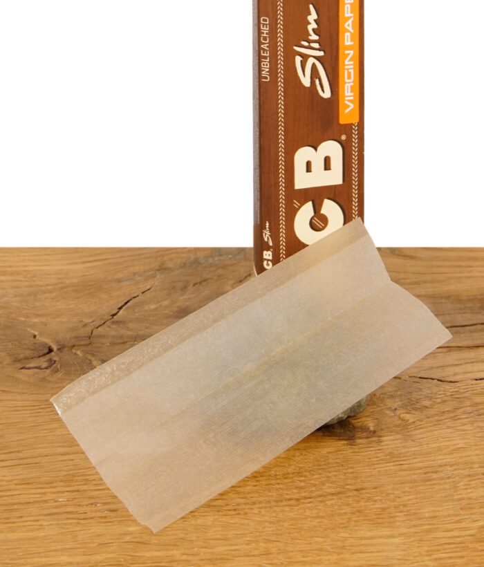 Ein einzelnes ungebleichtes OCB Virgin Paper im King Size Slim Format vor der Packung auf Holztisch