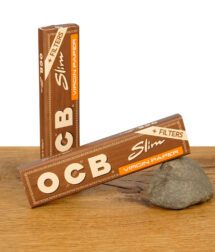 Zwei geschlossene Packungen OCB Virgin Paper King Size Slim mit integrierten Tips, braunes Design mit „+ Filters“-Hinweis