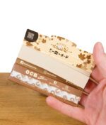 Geöffnete Packung OCB Slim Virgin Papers mit integrierten Tips, gehalten in der Hand – Innendesign mit Ahornblattmotiv