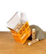 Geöffnete OCB Activ'Tips Extra Slim Packung mit Aktivkohlefiltern, zwei lose Filter liegen davor auf Holztisch