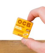 Kleine Schachtel OCB Activ'Tips Extra Slim 15er Pack ungebleicht, zwischen zwei Fingern gehalten – Vorderseite sichtbar