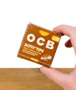 OCB Activ'Tips Slim ungebleicht, 50er Pack – Verpackung wird zwischen zwei Fingern gehalten, Vorderseite sichtbar