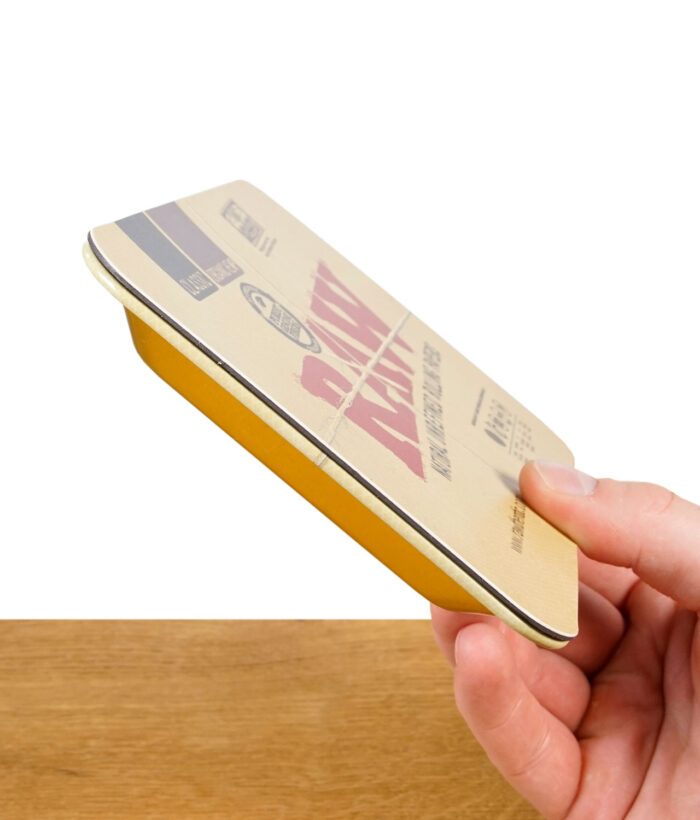RAW Magnet-Cover Mini aus Metall mit gelbem Rand, seitlich in der Hand gehalten – flache, stabile Ausführung sichtbar