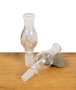 Zwei Black Leaf Flow Aktivkohleadapter aus Glas auf Holzuntergrund, einer stehend, einer liegend