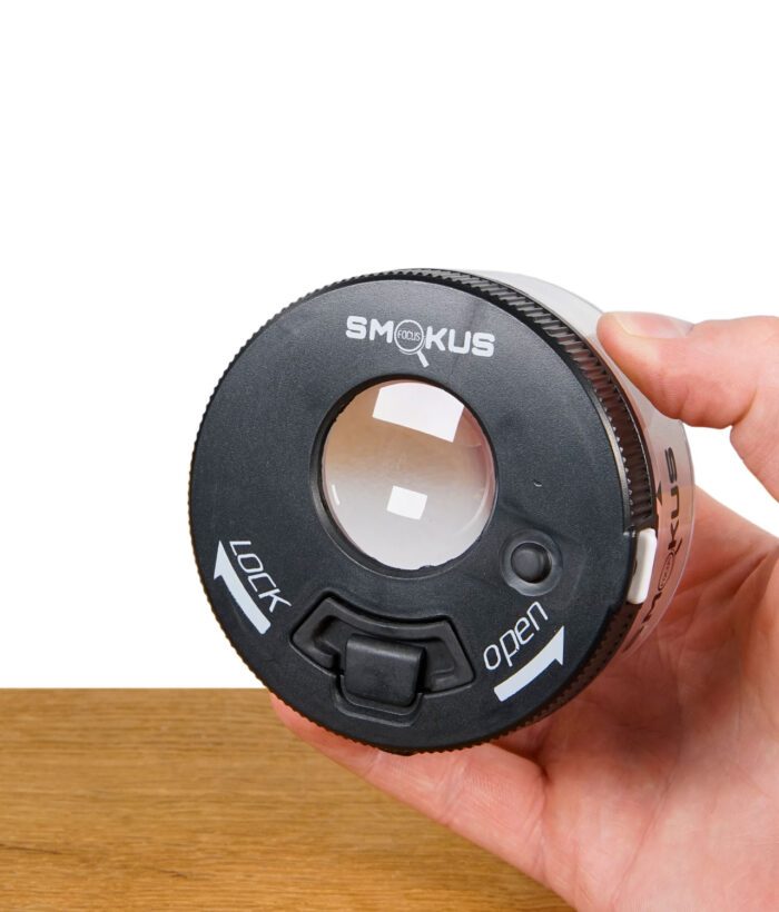Hand hält den Smokus Focus Behälter, Fokus auf Deckel mit Sichtfenster, Lock-Schieber und Öffnungsmechanismus