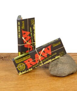 Zwei Verpackungen der RAW Black Green Organic Paper 1 1/4 Size auf Holzuntergrund