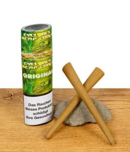 Cyclones Hemp Blunts Original – zwei vorgedrehte Hanf-Cones vor grüner Verpackung auf Holzuntergrund