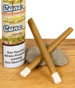 Zwei vorgerollte Cyclones Hemp Cones Cane mit Holzfilter neben der Verpackung auf Holztisch